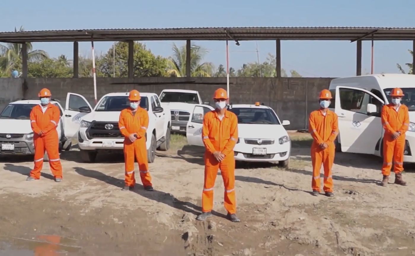 Grupo CCT field crew in orange coveralls in front of the company fleet
